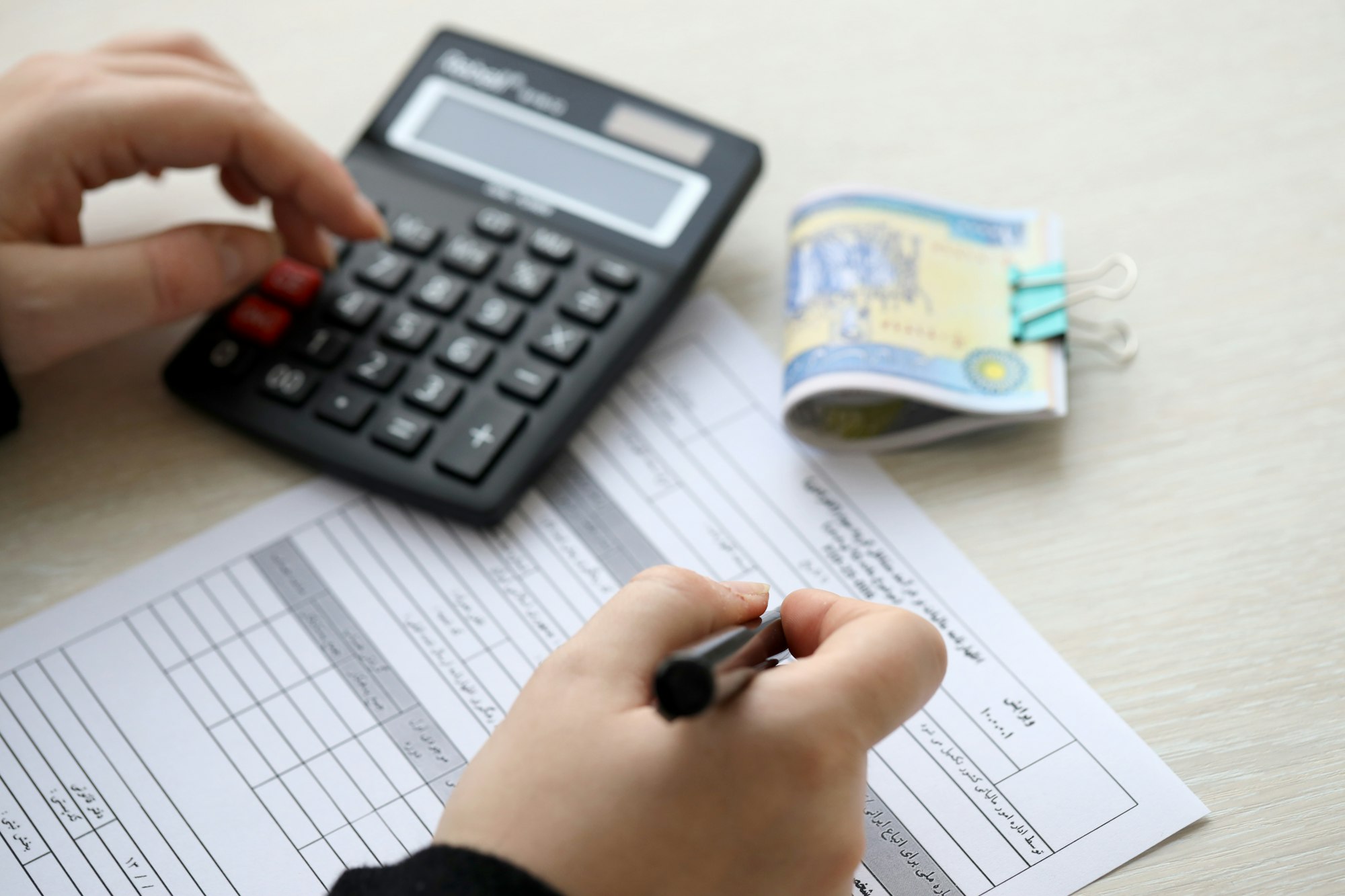 Accountant start to fill Iranian tax form on office table. Taxation period